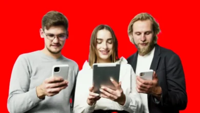 Two young men and a girl between them, each of them holding a phone and she holding a tablet