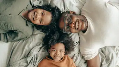 Father, mother and son on the bed looking at the camera happily