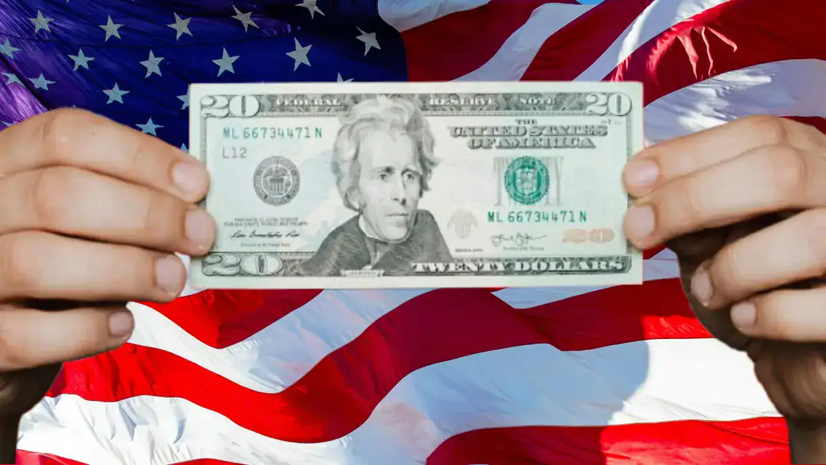 Two hands holding $20 bills with an American flag in the background