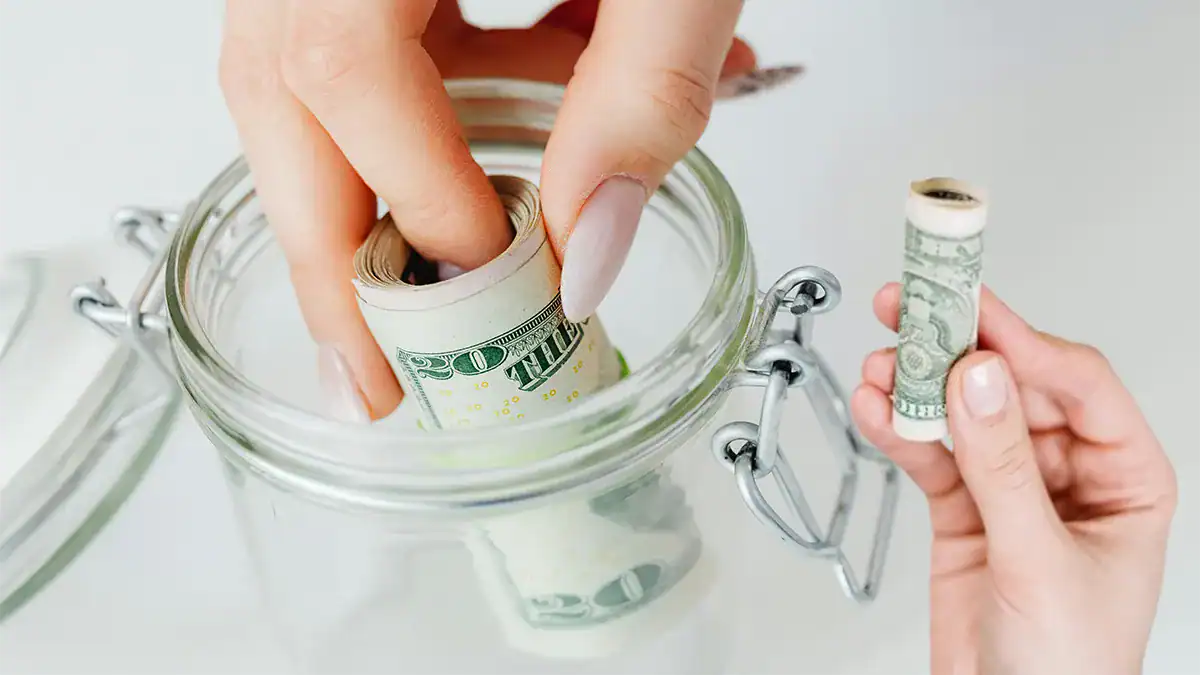 Hand putting money in piggy bank